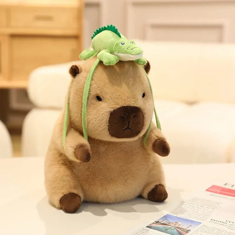 Kawaii plush toy capybara with a green lizard on its head on a table.