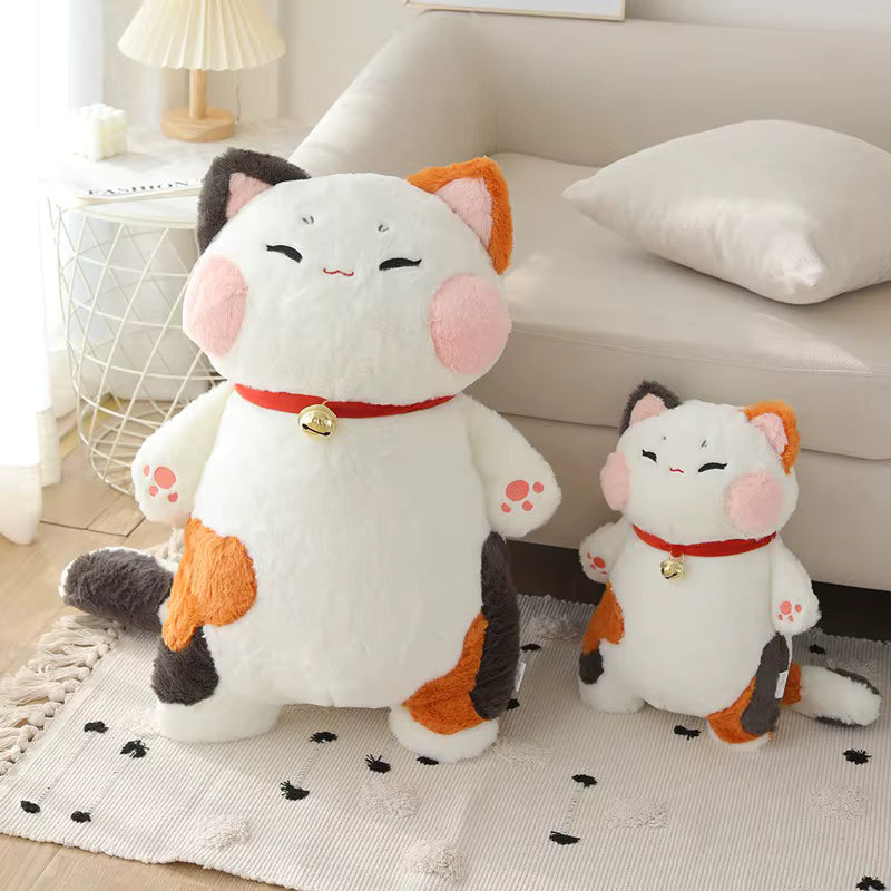 Two plush cat toys on a rug with a couch and lamp in the background
