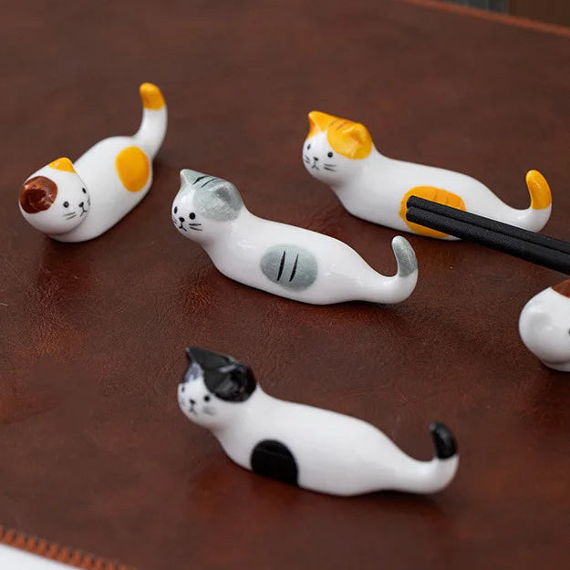 Cat-shaped ceramic kawaii chopstick holders on a wooden surface