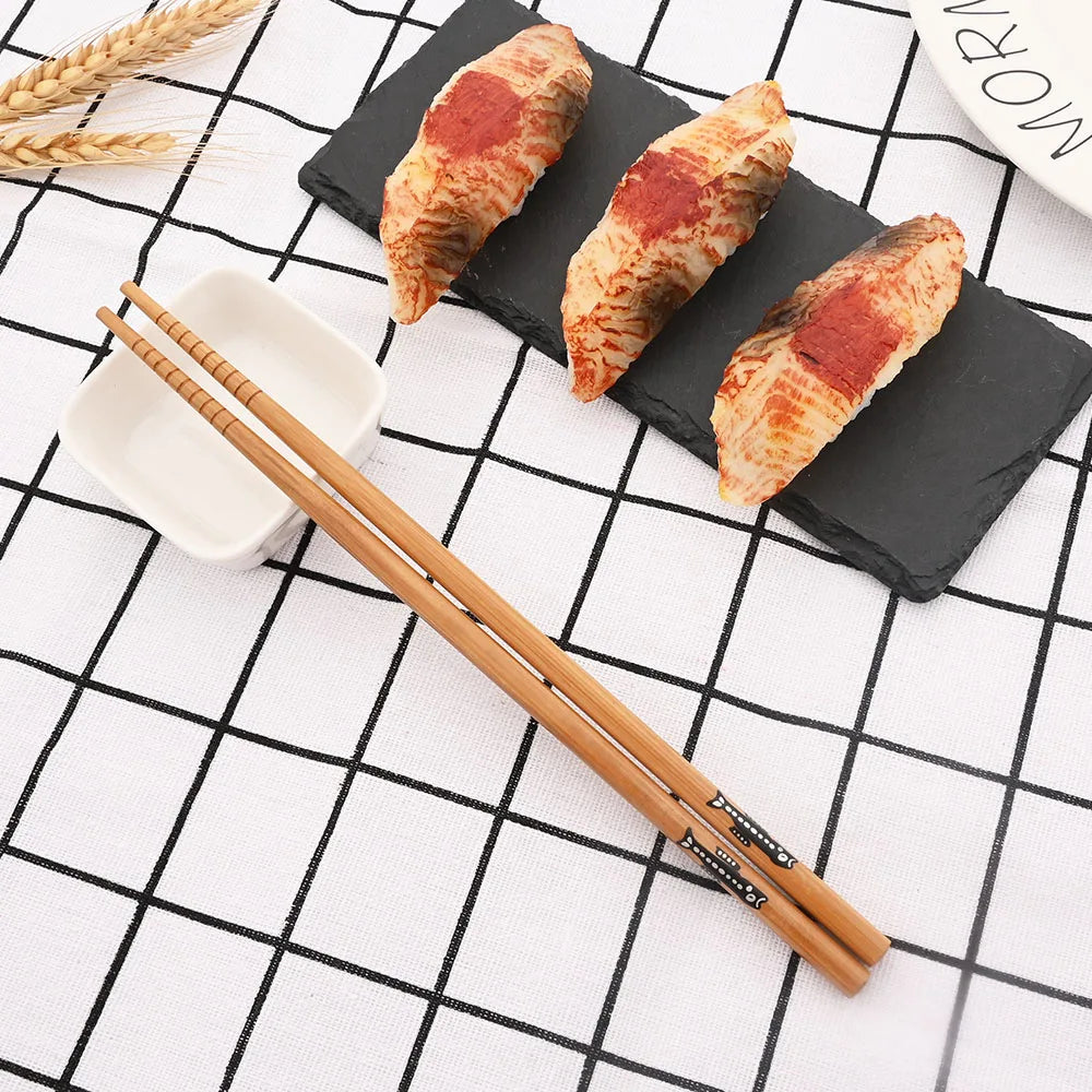 Three croissants on a black slate with wooden kawaii chopsticks on a grid-patterned surface.