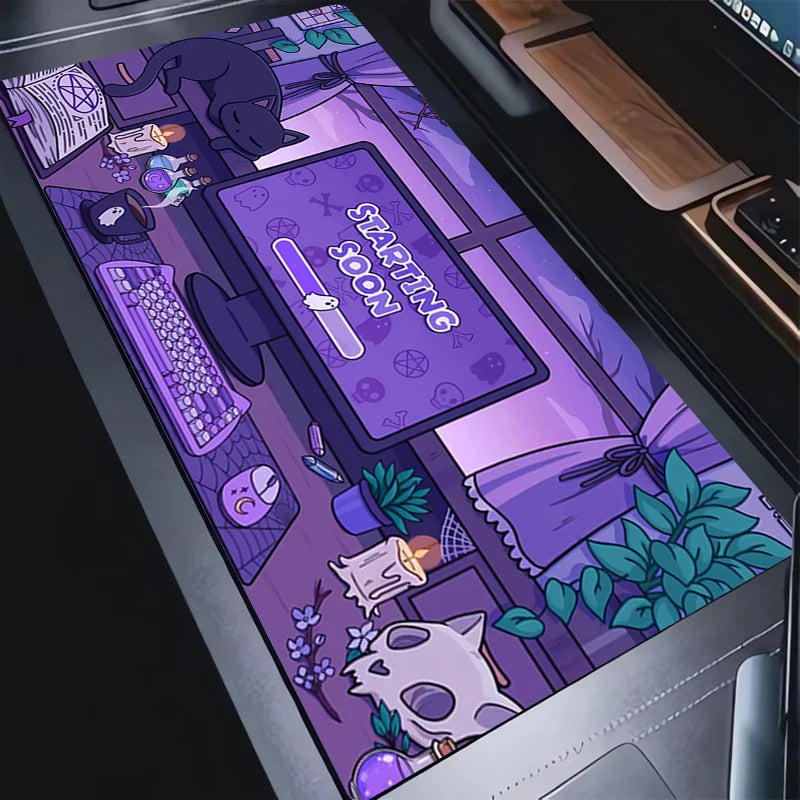 A long desk mat with a detailed purple and black cartoon illustration, shown laid out on a laptop keyboard. The illustration features a desk setup with a computer monitor displaying 'STARTING JOON', a cat, a skull, plants, and mystical symbols.