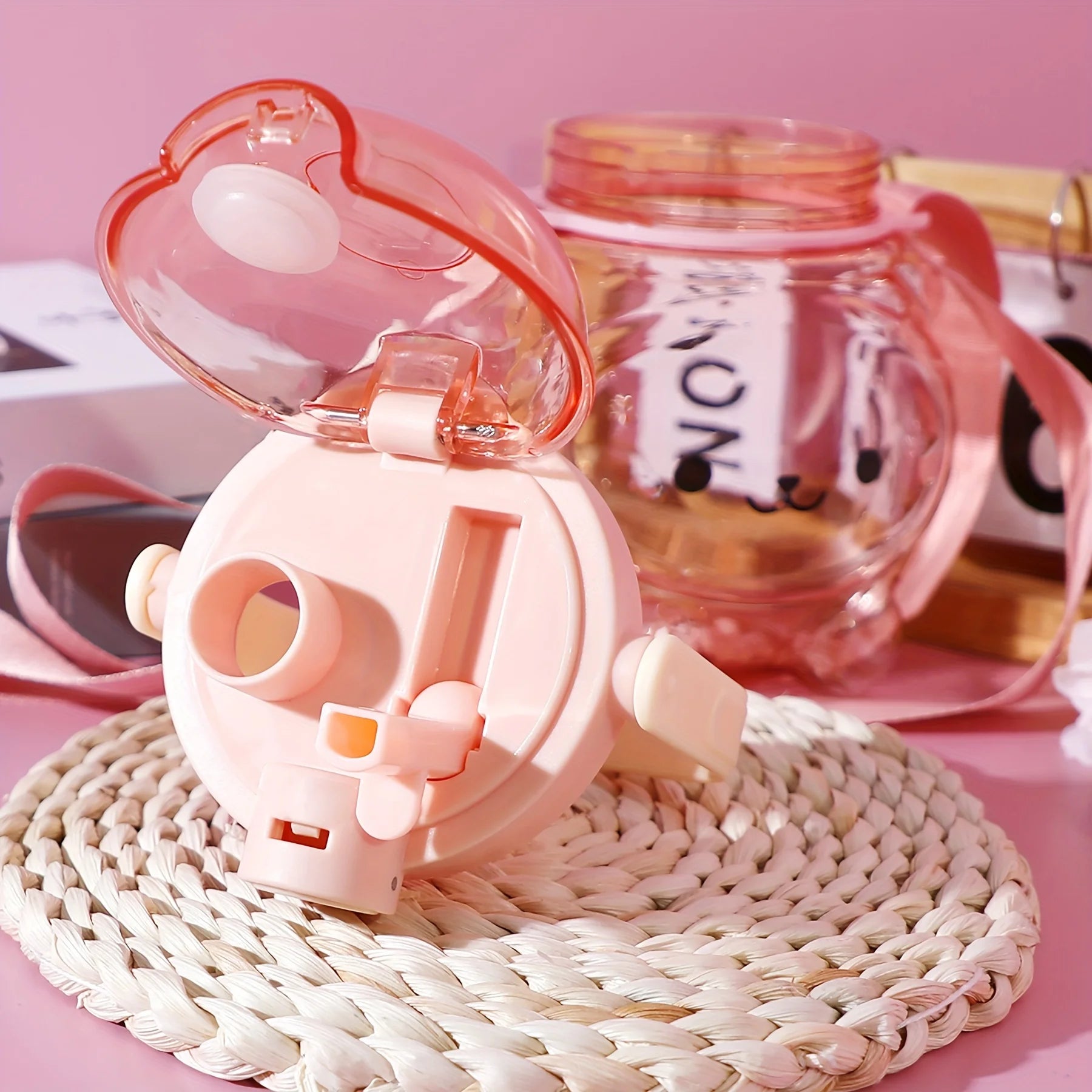 Pink cartoon-style kawaii water bottle with a transparent lid on a pink surface