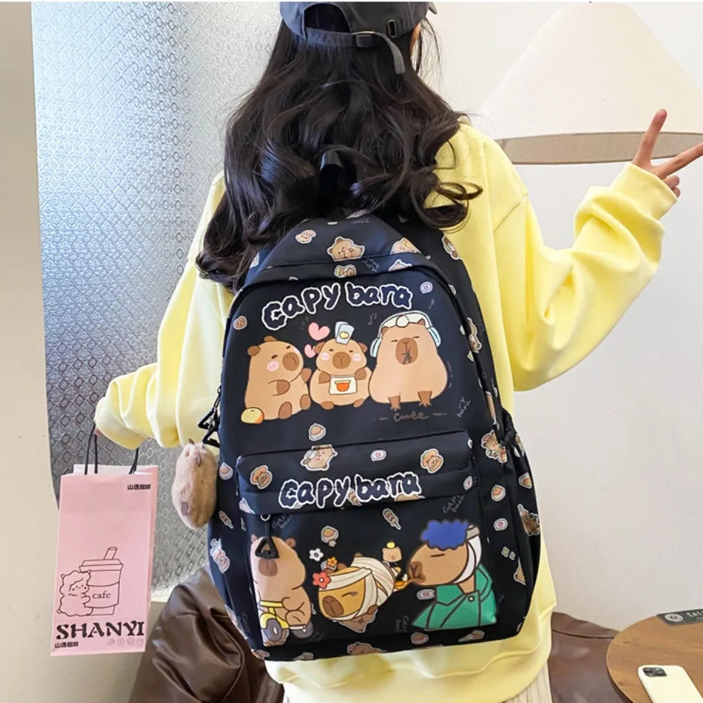Person wearing a black backpack with Kawaii cartoon designs and 'Capybara' text, holding a pink bag with 'SHANY' branding.