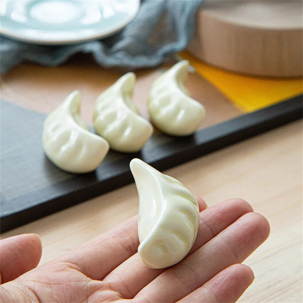 White kawaii dumpling-shaped cookies on a wooden surface with a hand holding one cookie.