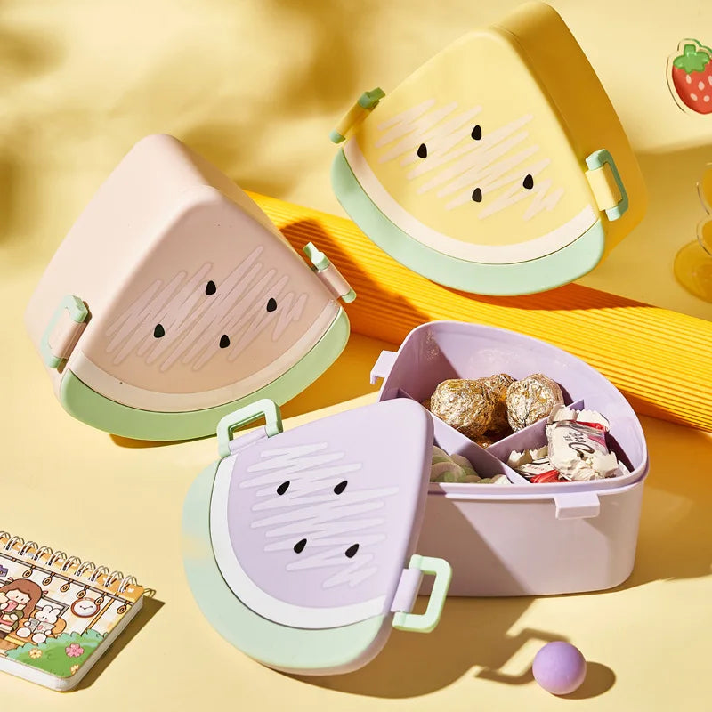 Three colorful children's kawaii bento boxes shaped like watermelon slices on a yellow background.