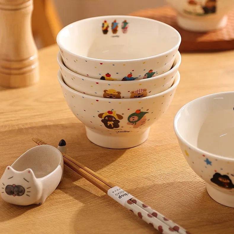 Set of small white kawaii ramen bowls with colorful designs on a wooden table.