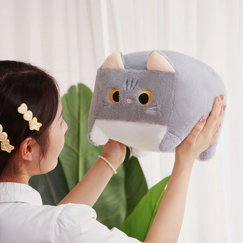 Person holding a gray cat-shaped kawaii plush toy against a white curtain background