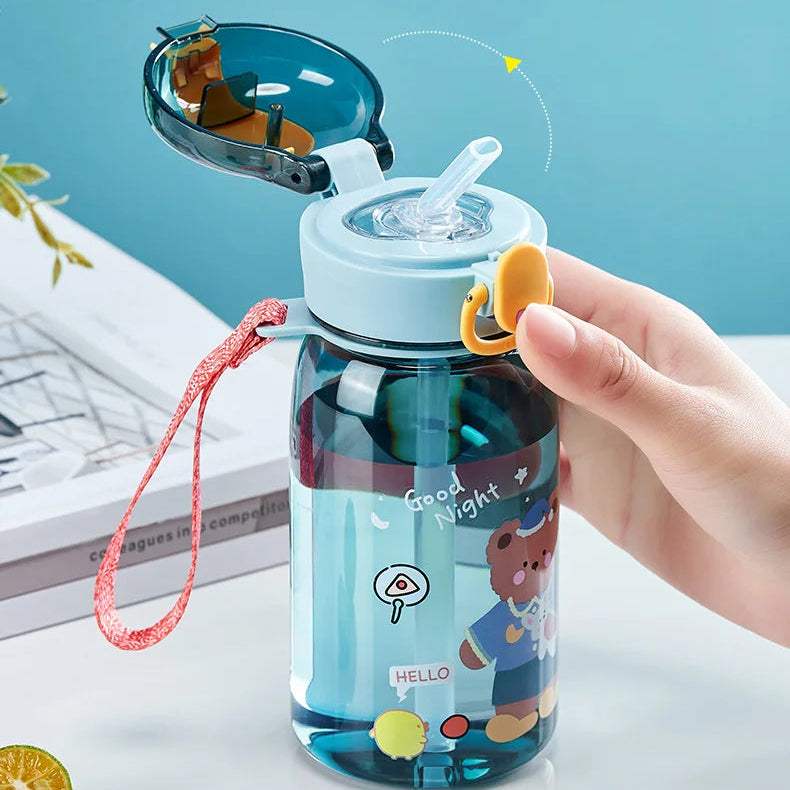 Children's kawaii water bottle with cartoon design held by a hand against a light blue background.