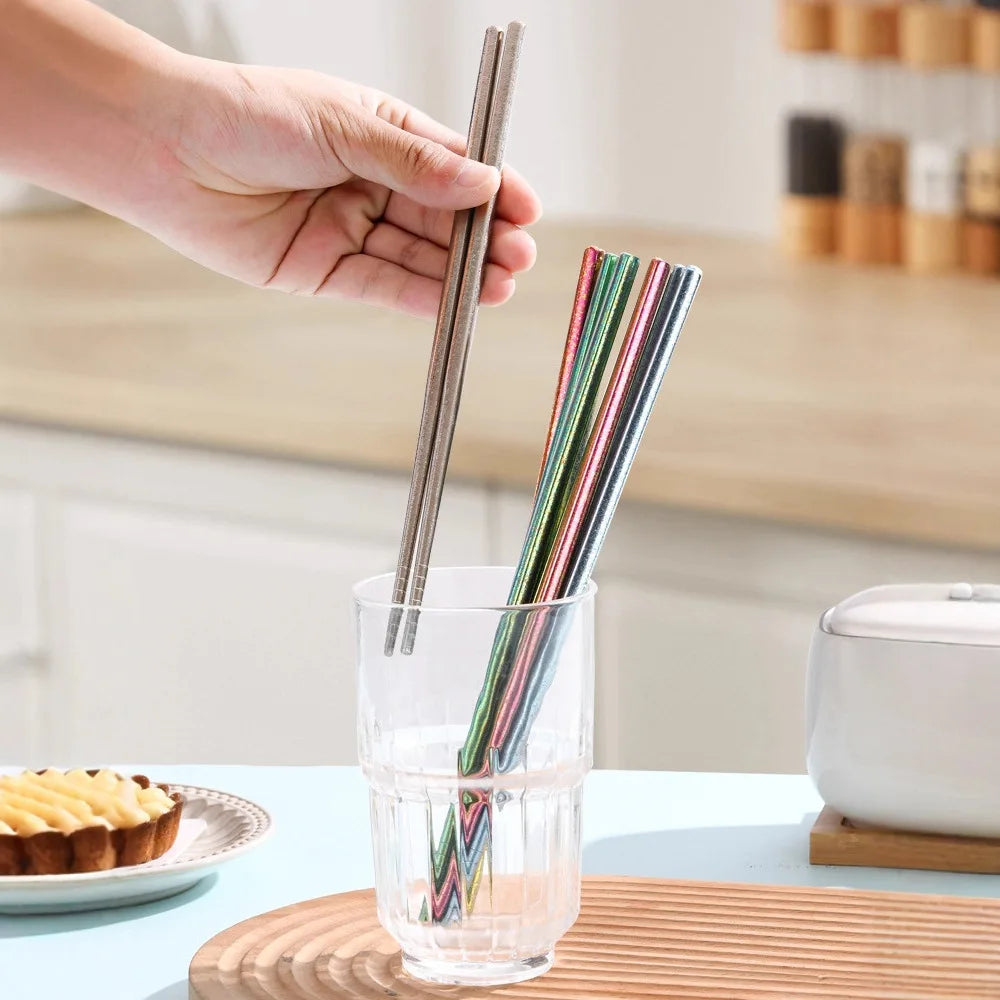 Hand holding kawaii chopsticks over a glass with a blurred kitchen background