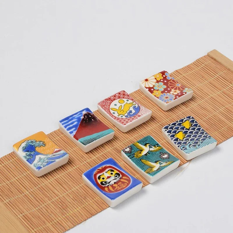 Set of small ceramic kawaii chopstick holders with various designs on a wooden surface