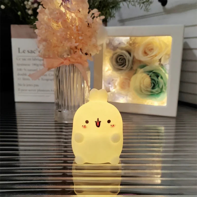 Cute kawaii chick-shaped night light on a reflective surface with flowers in the background