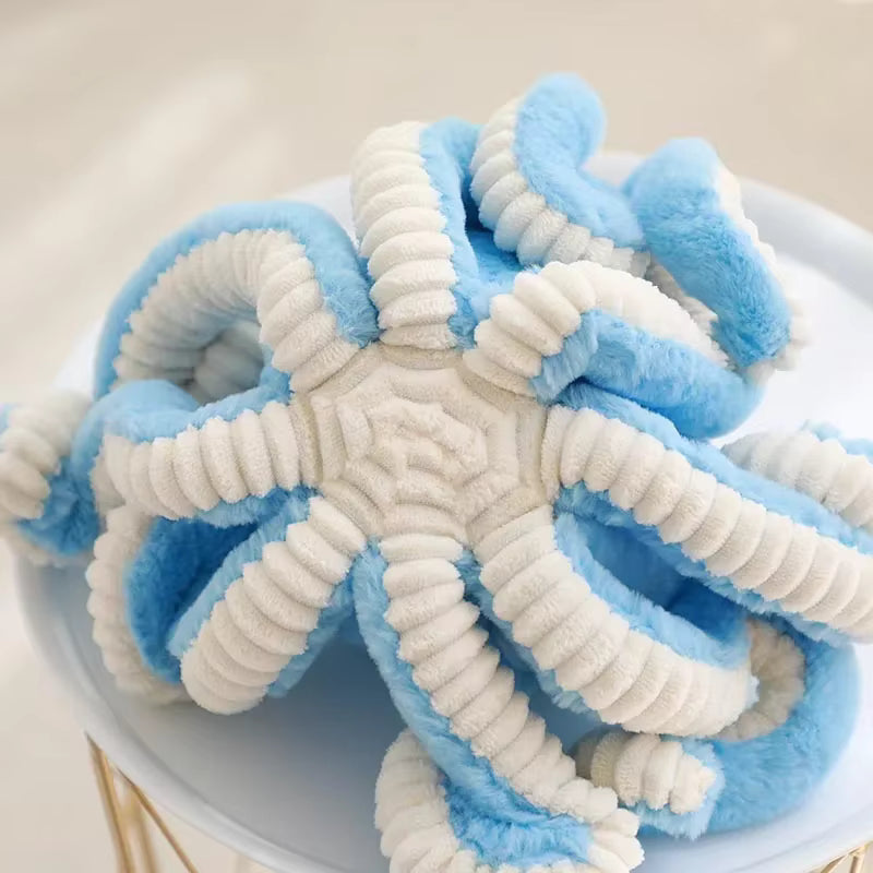 A plush star-shaped pet toy in light blue and white ribbed fabric, displayed on a white plate.