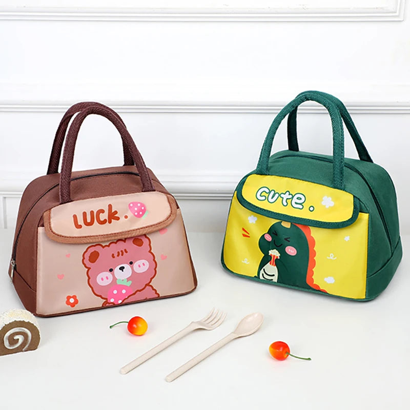Two cartoon-themed kawaii lunch bags on a white surface with utensils and a cake.