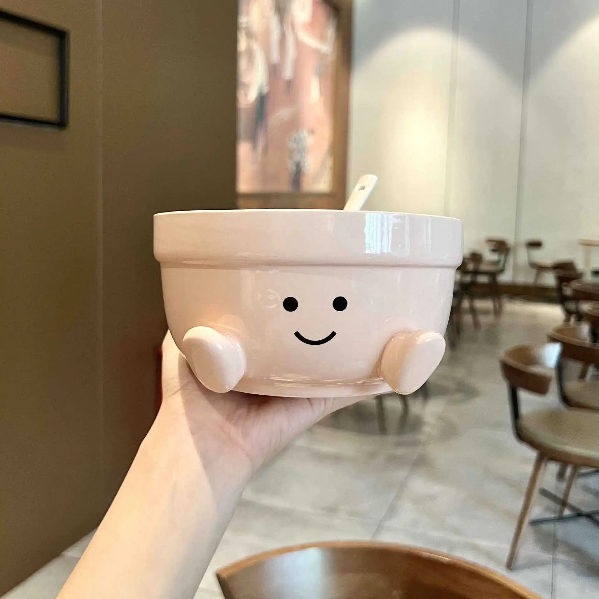 Cute ceramic kawaii bowl with a smiley face held in a hand in a casual setting.