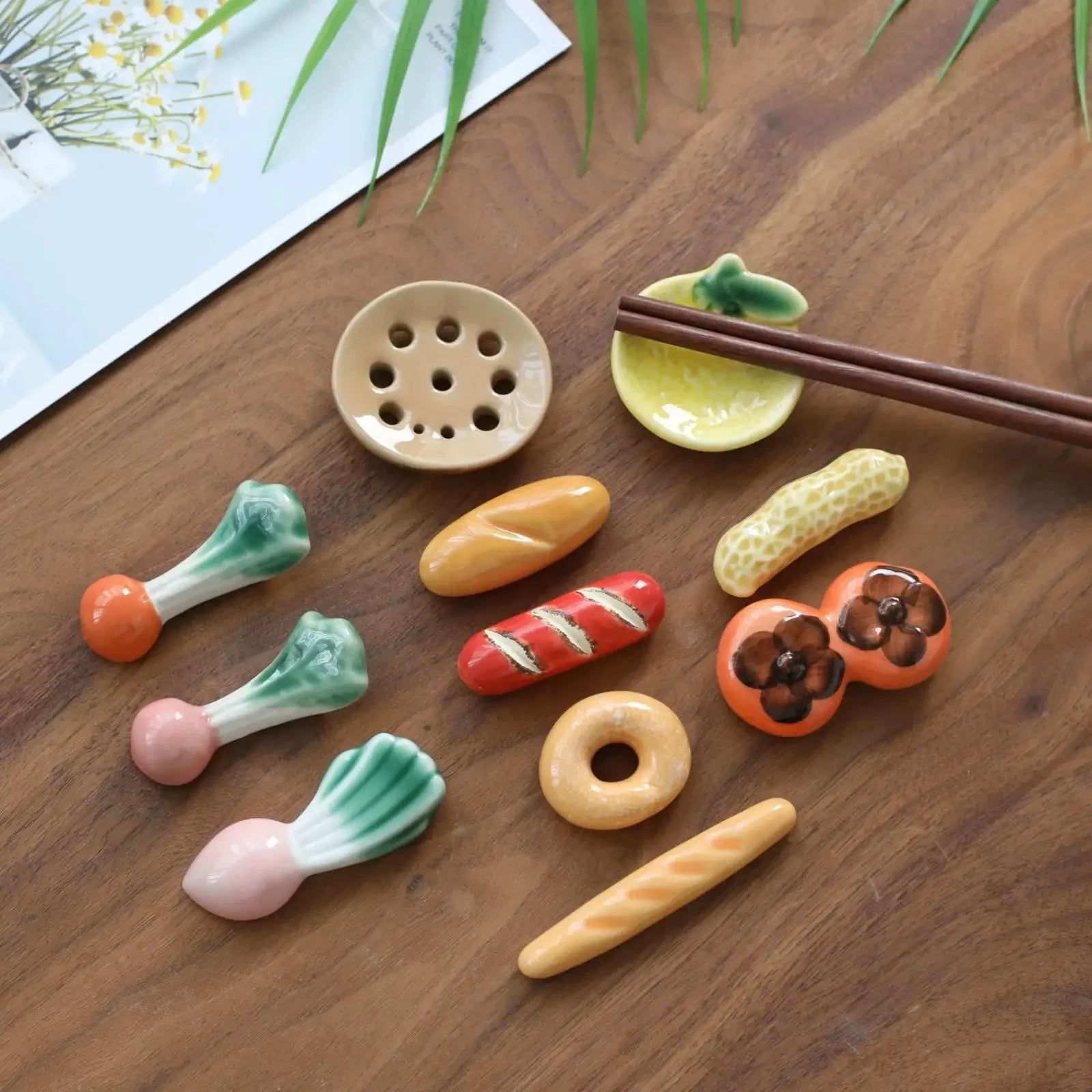 Set of ceramic vegetable-shaped kawaii chopstick holders on a wooden surface with chopsticks.