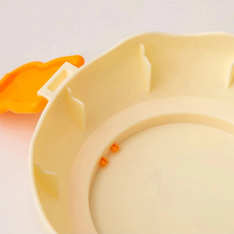 Close-up of a beige plastic kawaii food container with orange accents on a light pink background