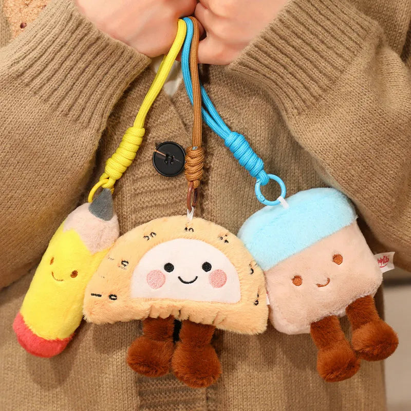 Kawaii plush keychains shaped like cartoon characters attached to a string, held by a person wearing a brown sweater.