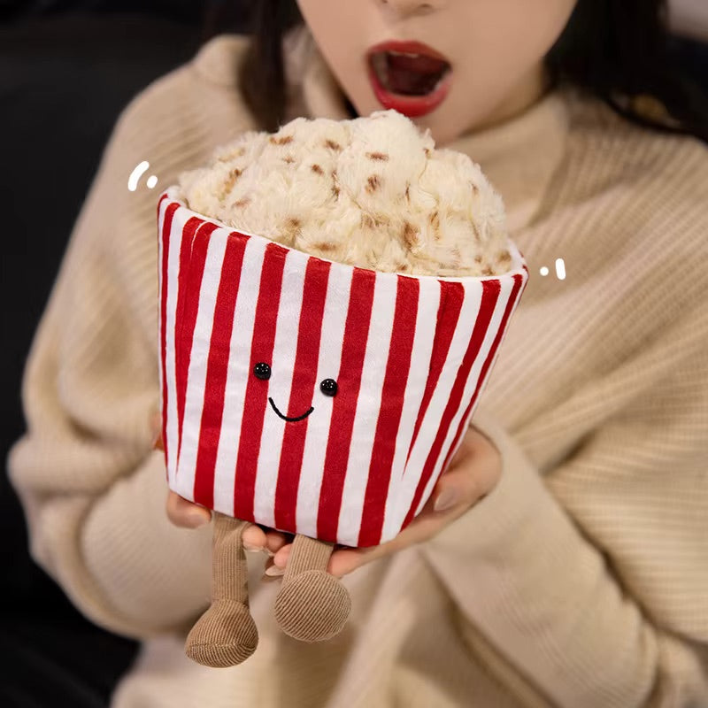 Kawaii plush toy resembling a popcorn bucket with legs and a smiling face being held by a woman.