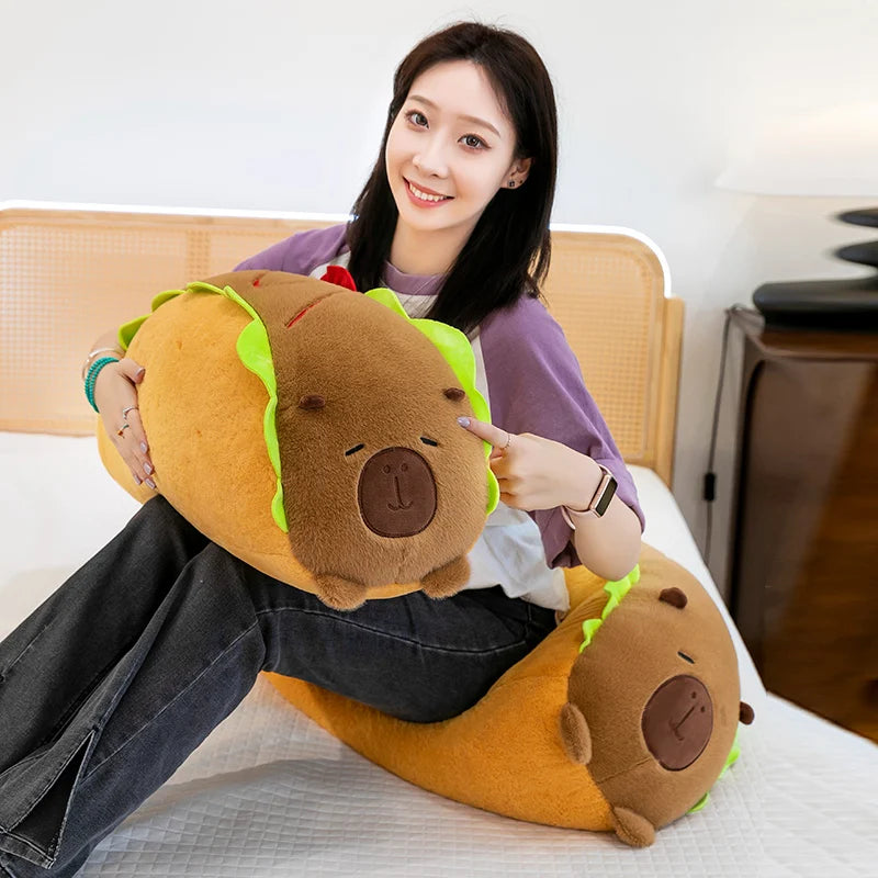 Person holding a large, kawaii plush hot dog toy on a bed.