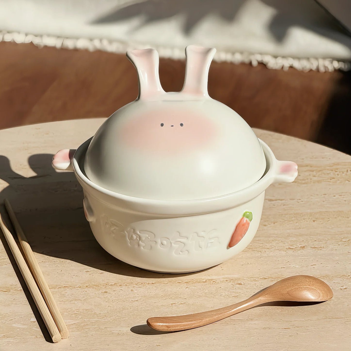Ceramic kawaii bowl with rabbit design on a wooden table with chopsticks and a spoon, branded 'YUTOPIA'.