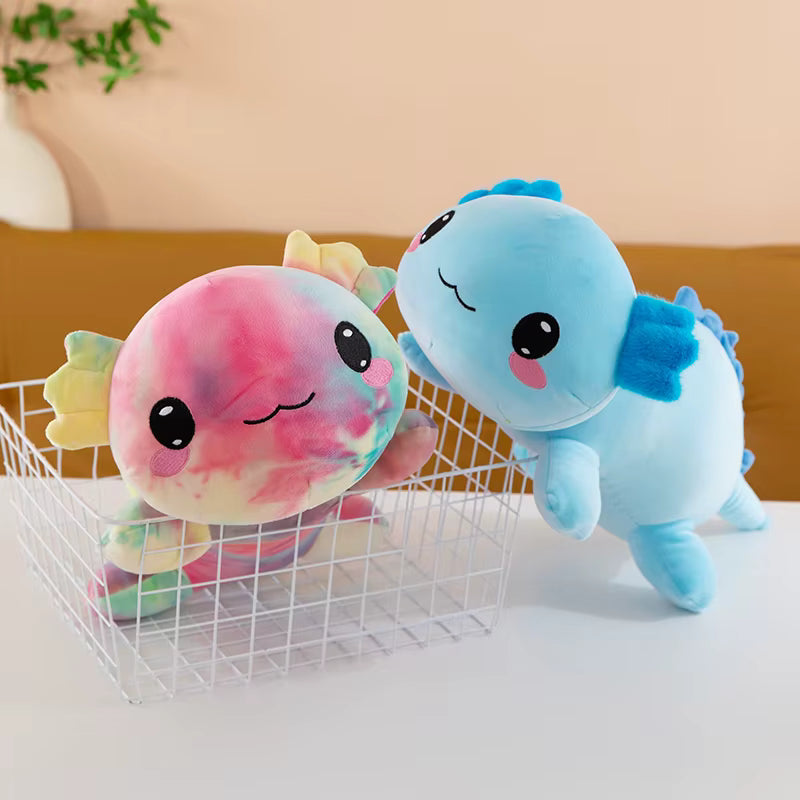 Two colorful plush toys, one pink and one blue, on a white surface with a neutral background.