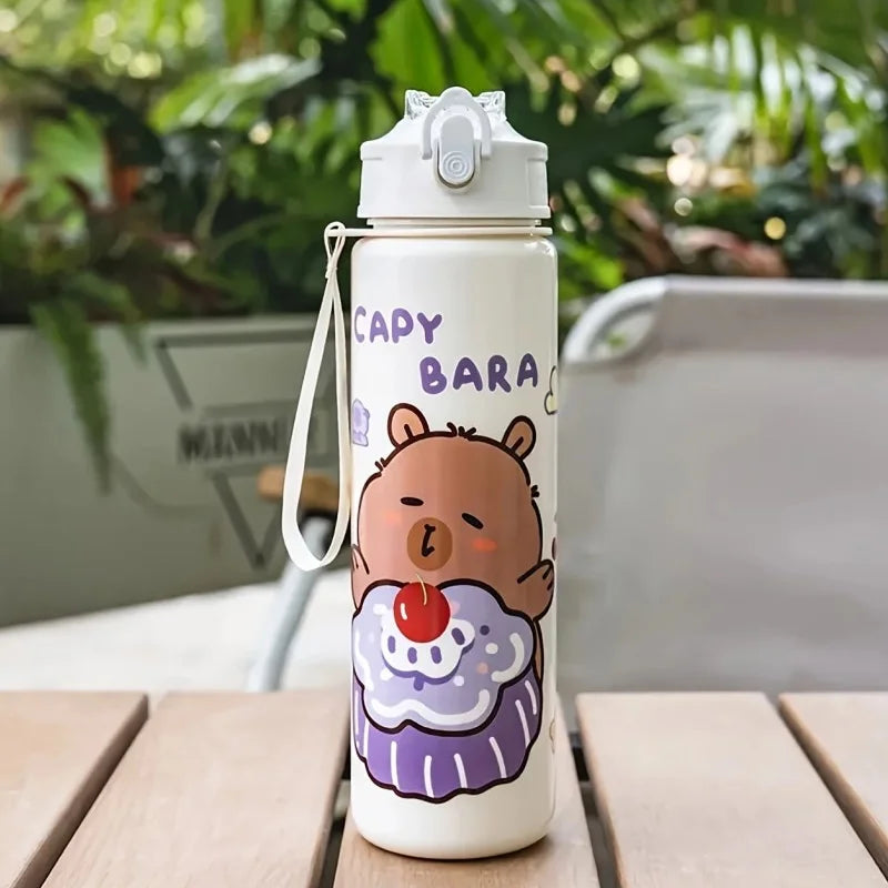 White kawaii water bottle with cartoon bear design and 'Capybara' text on a wooden table outdoors.