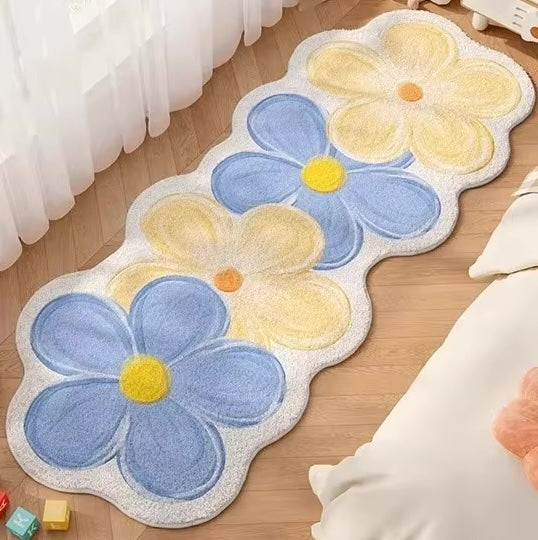 A rug with four flowers in yellow and blue on a wooden floor.
