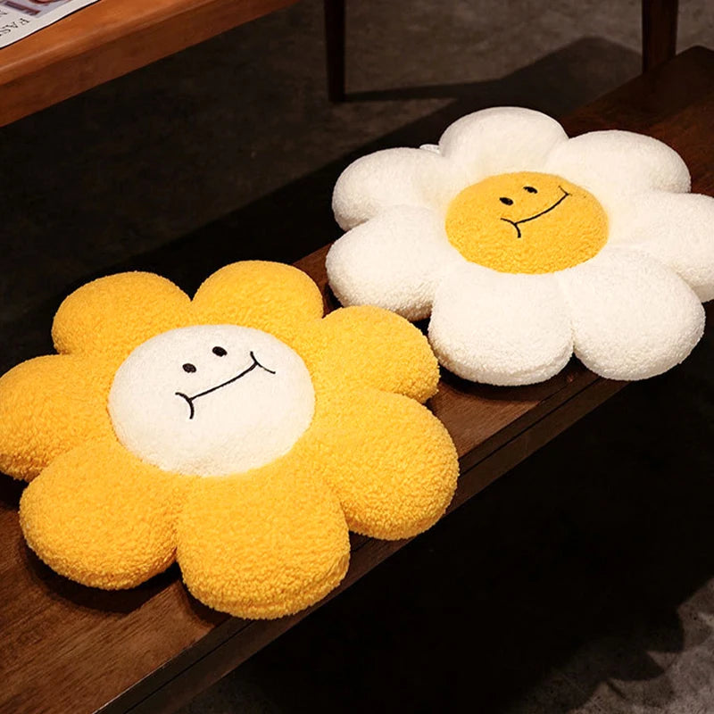 Two flower-shaped kawaii cushions with smiley faces on a wooden surface.