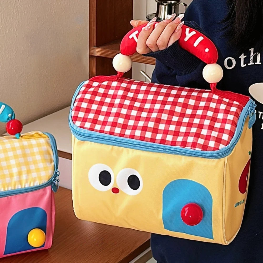 Child's toy kawaii lunch bag with a checkered pattern held by a person, with another similar suitcase on the floor.