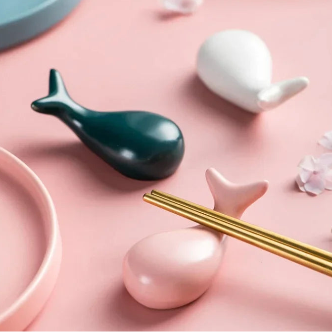 Decorative kawaii chopstick holders including a green whale-shaped object, white ceramic piece, and gold chopsticks on a pink surface with text about baking dish features.