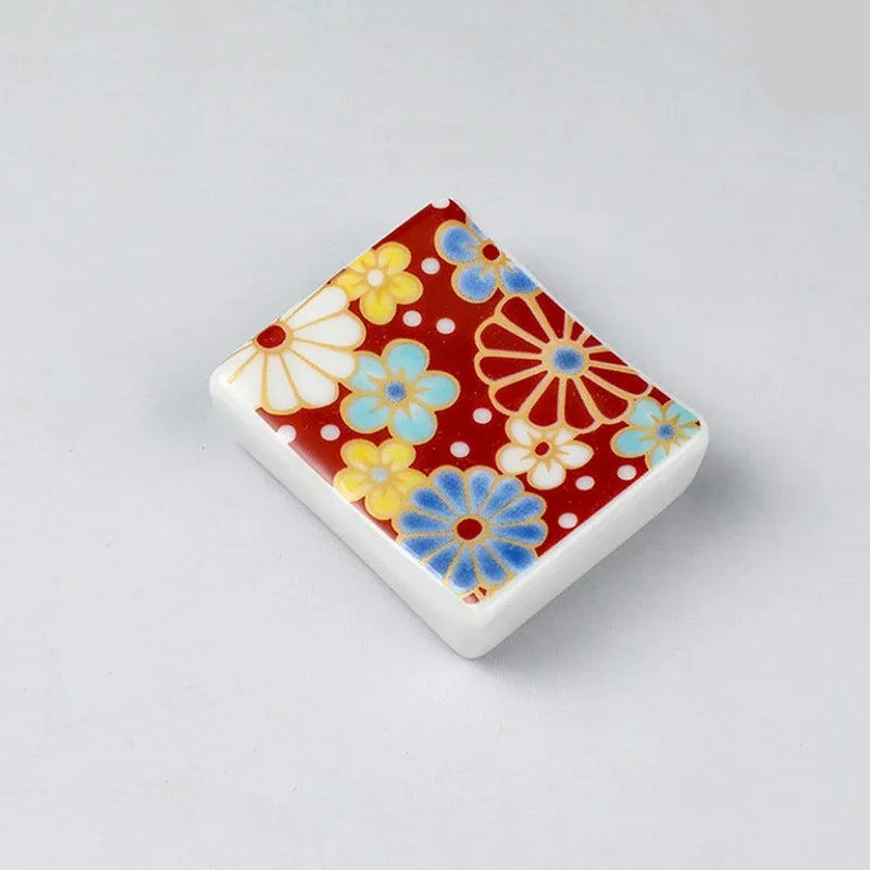Rectangular ceramic kawaii chopstick holders with floral pattern on a gray background