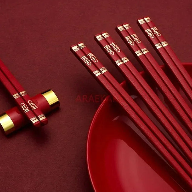 Red kawaii chopsticks with gold accents on a red background