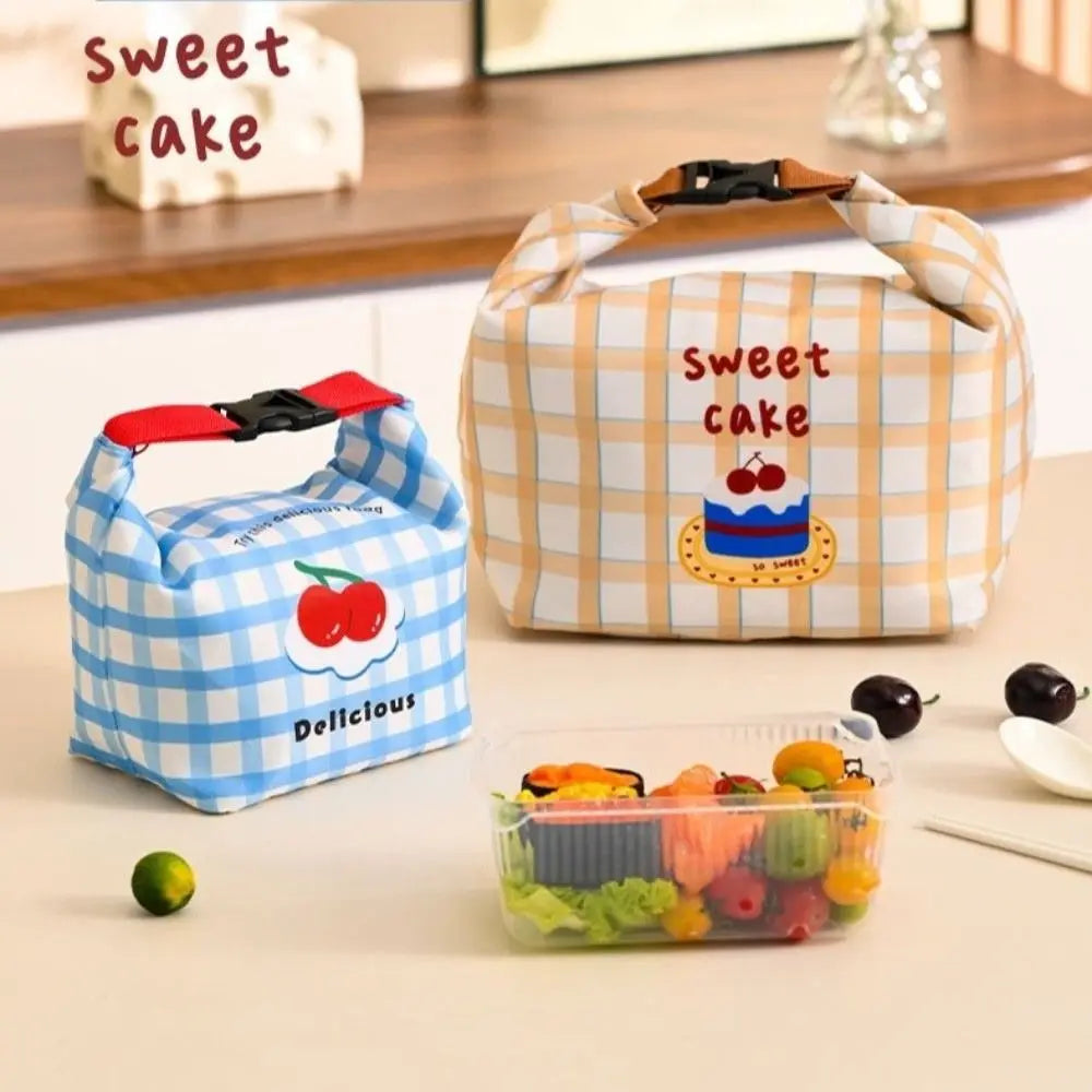 Two cartoon-themed kawaii bento boxes with 'sweet cake' and 'delicious' text on a table.