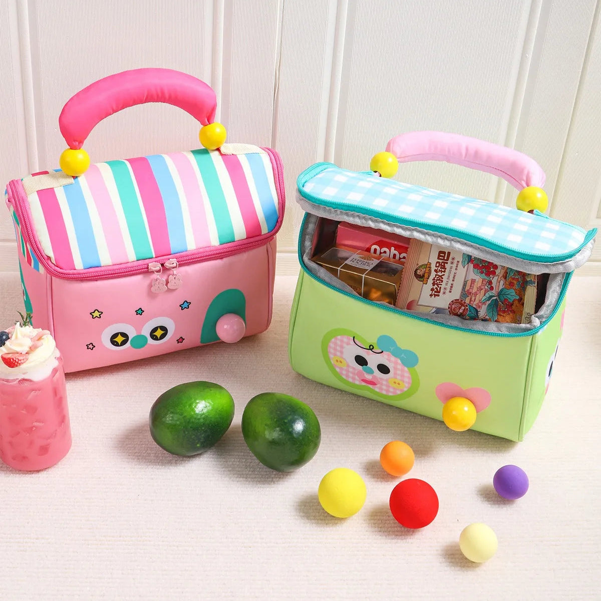 Two colorful children's kawaii lunch bags with toys and books on a light wooden floor.
