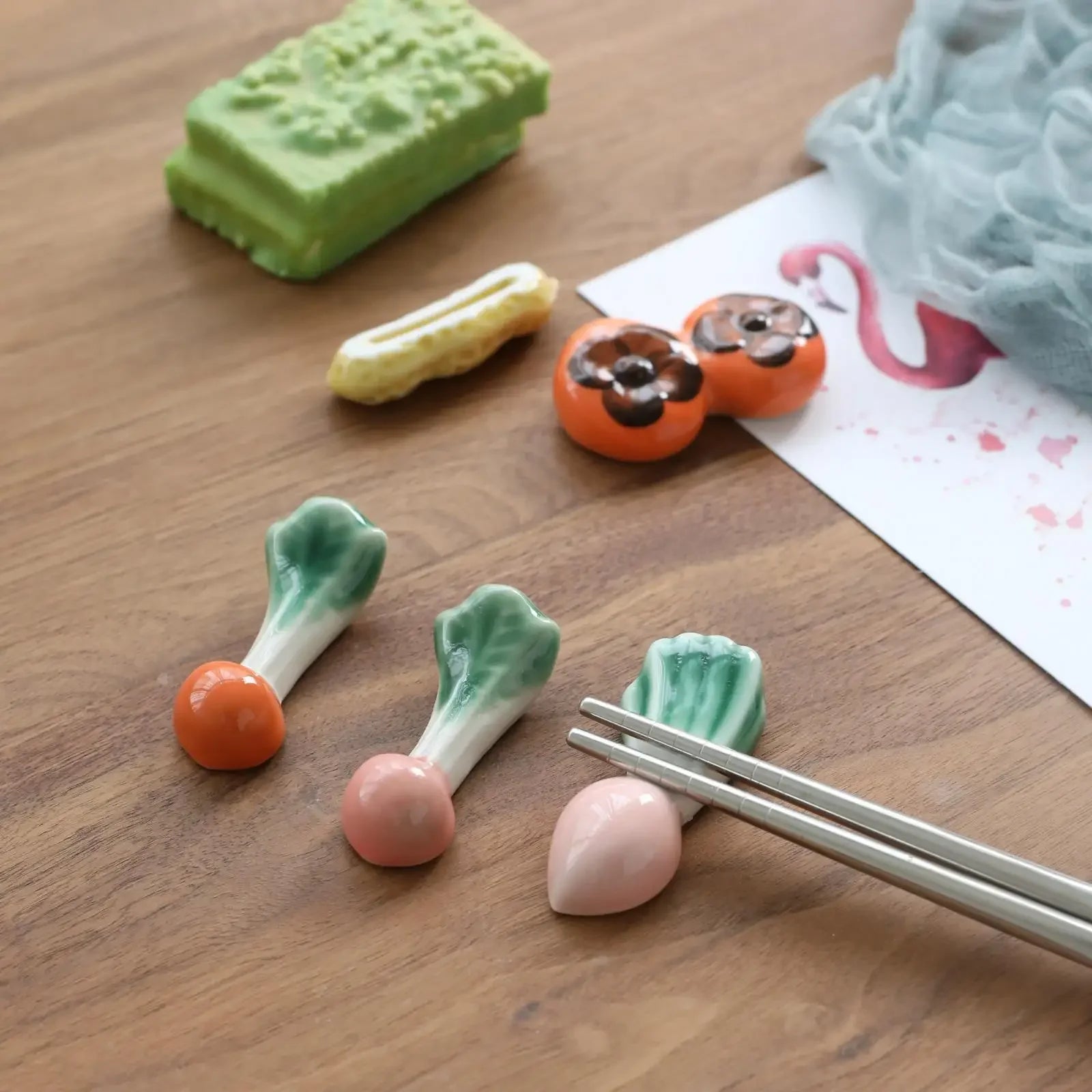 Various small food-shaped kawaii chopstick holders on a wooden surface with chopsticks.
