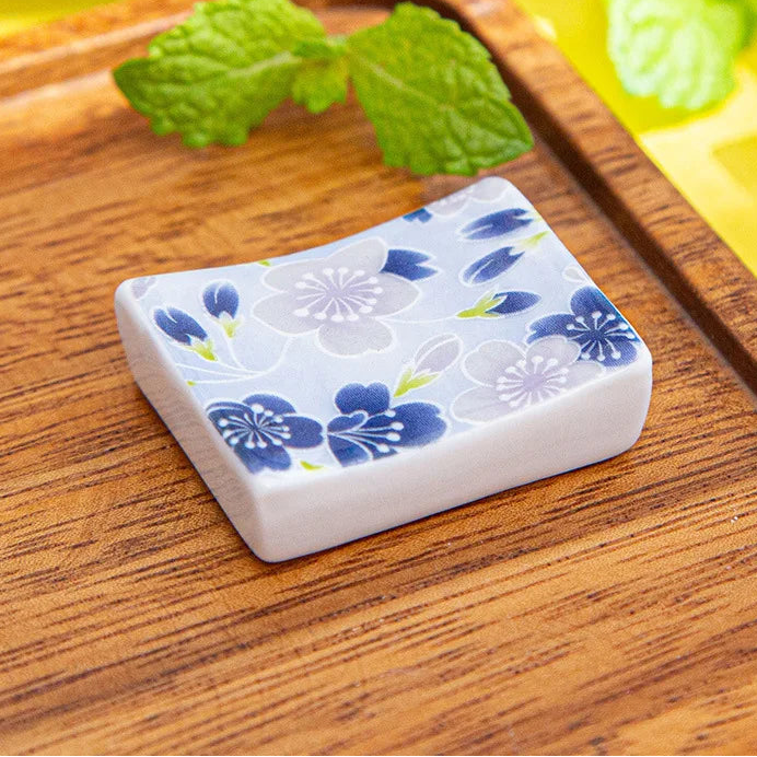 Square ceramic kawaii chopstick holders with floral design on a wooden surface