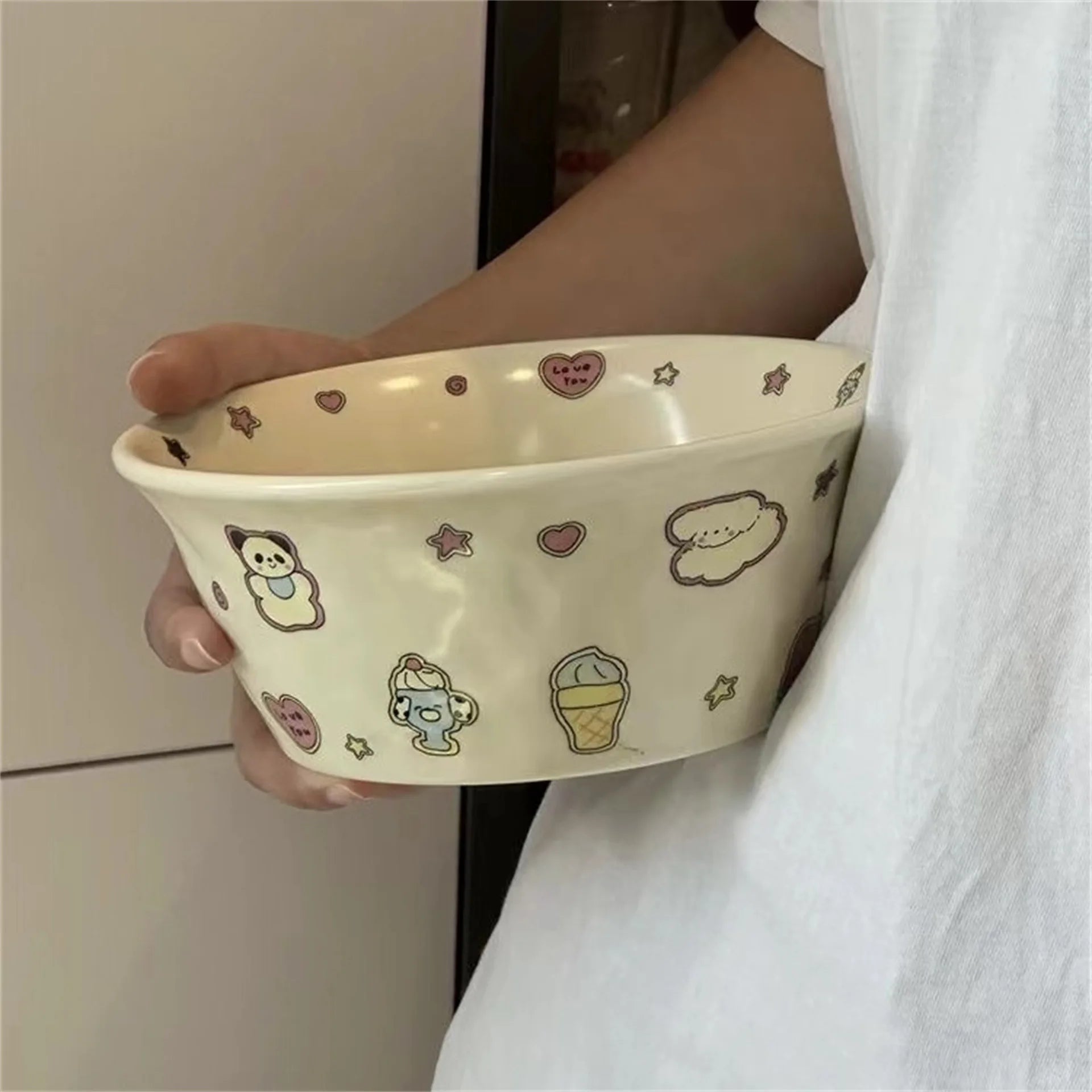 Person holding a decorative ceramic kawaii ramen bowl with cartoon illustrations.