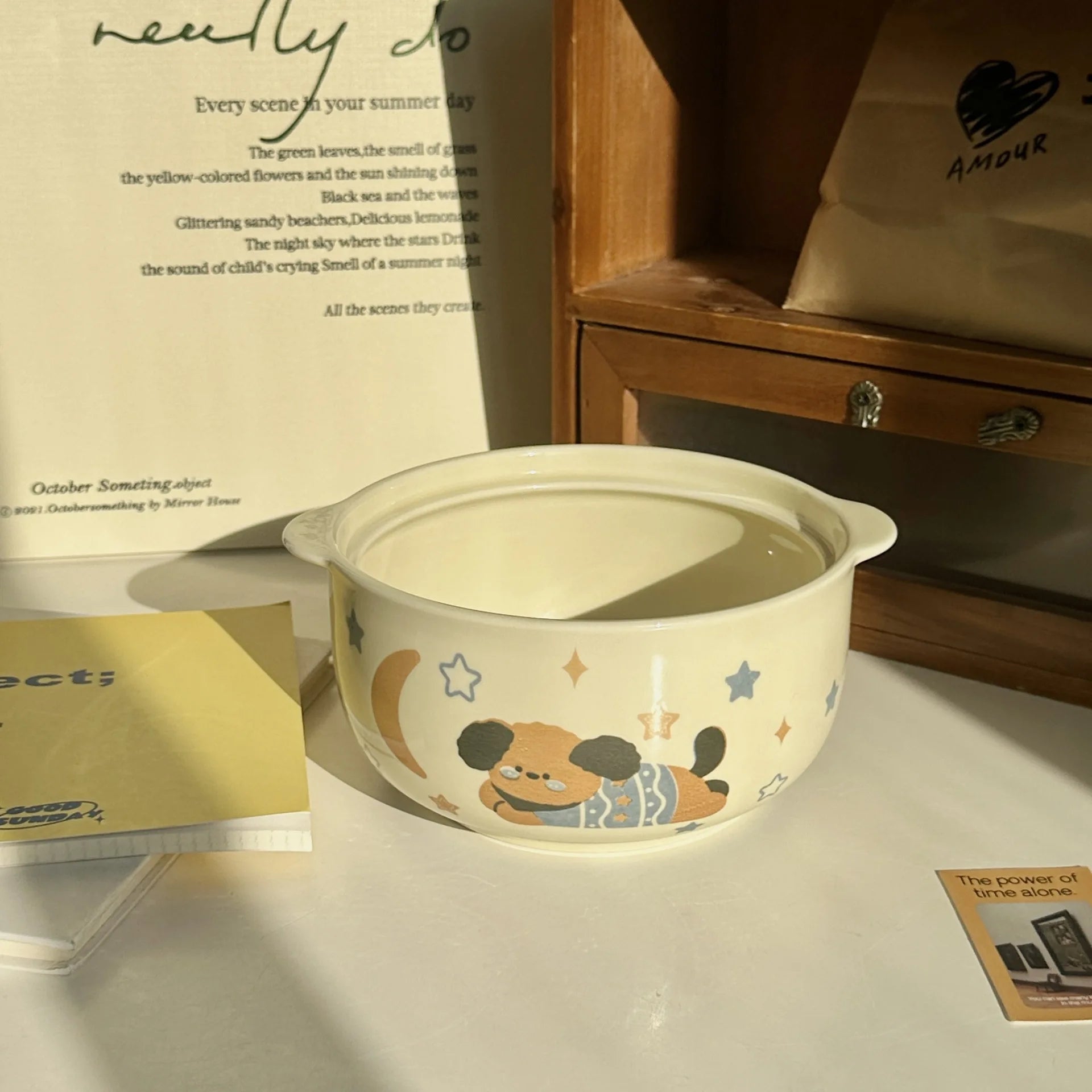 Ceramic kawaii ramen bowl with cartoon design on a surface with books and a wooden shelf in the background.