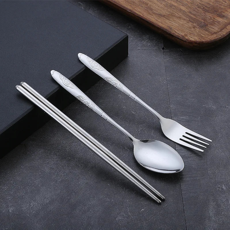 Stainless steel kawaii utensils set with spoon, fork, and chopsticks on a dark surface.