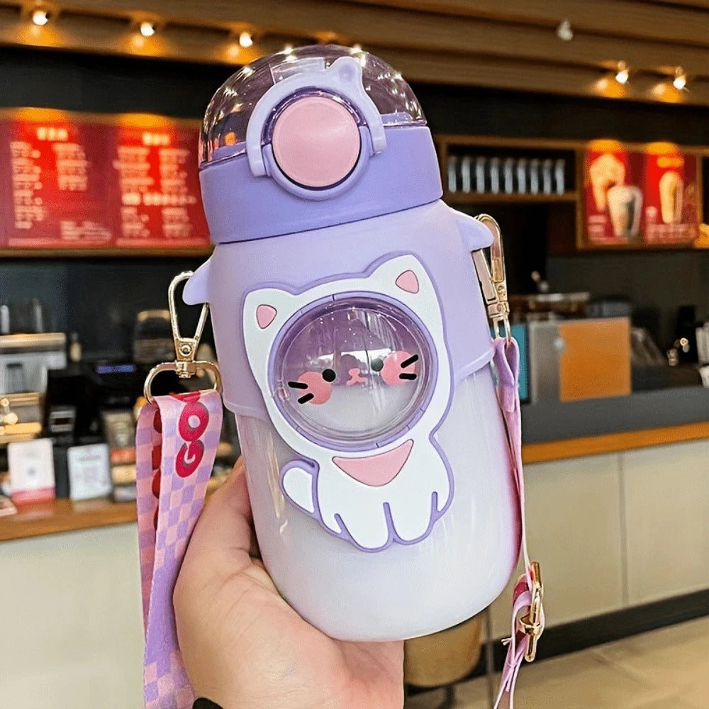 Cute purple kawaii water bottle with cat design held in a hand, blurred cafe interior in the background