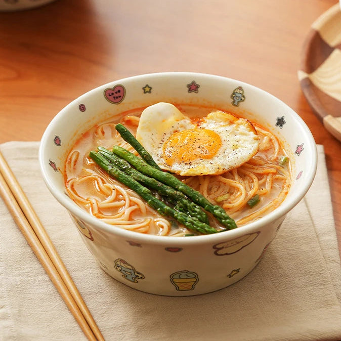 Kawaii ramen bowls of noodles with an egg and asparagus on a wooden table