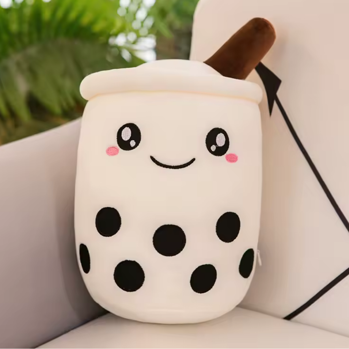 Kawaii plush toy resembling a bubble tea cup with a smiling face on a couch.
