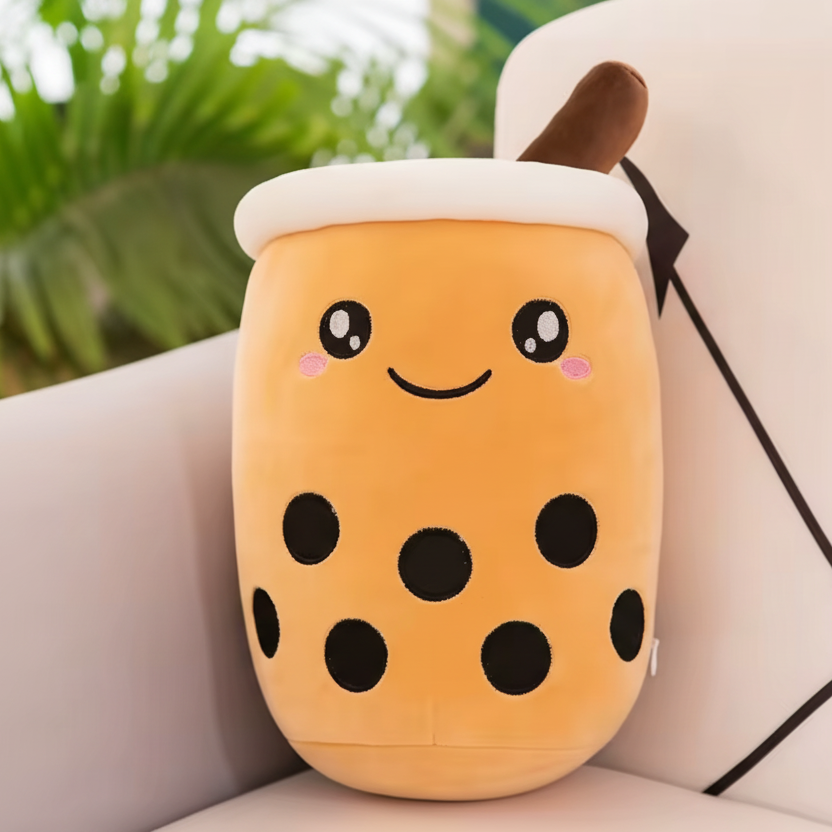 Kawaii plush toy shaped like a bubble tea cup with a smiling face on a couch.