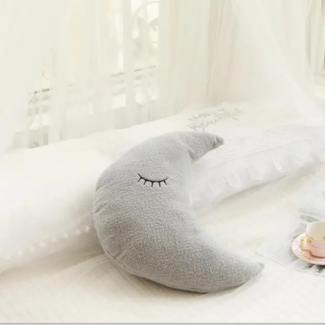 Gray crescent moon-shaped kawaii pillow with a face on a white surface