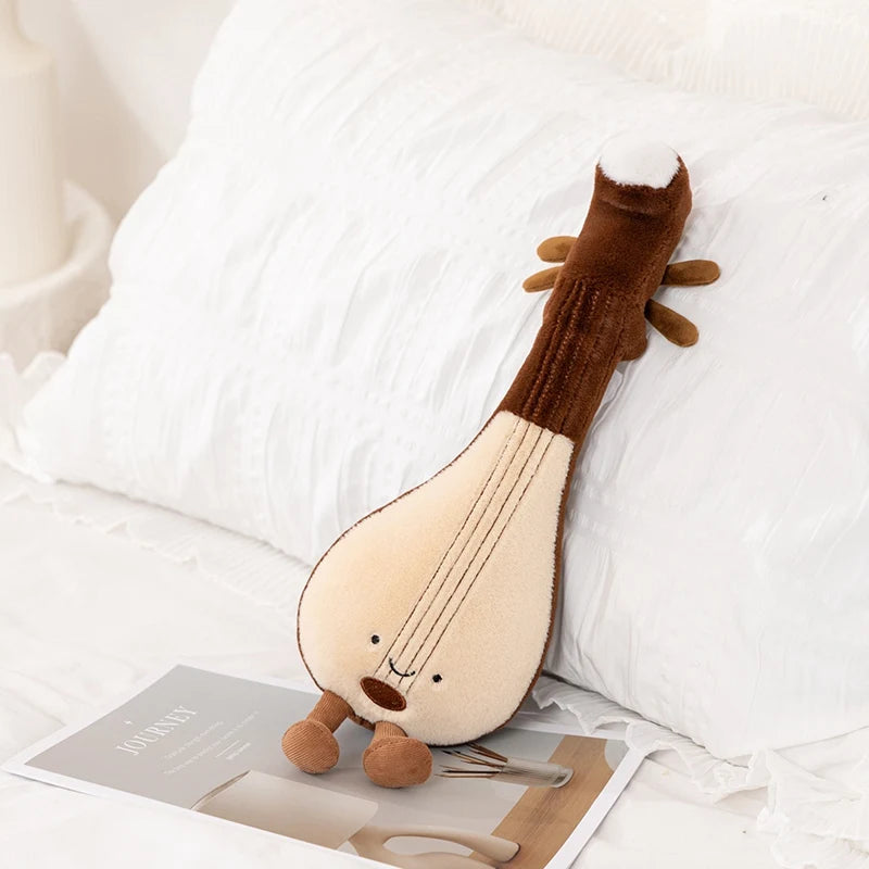 Kawaii plush toy resembling a lyre on a white surface with a magazine underneath