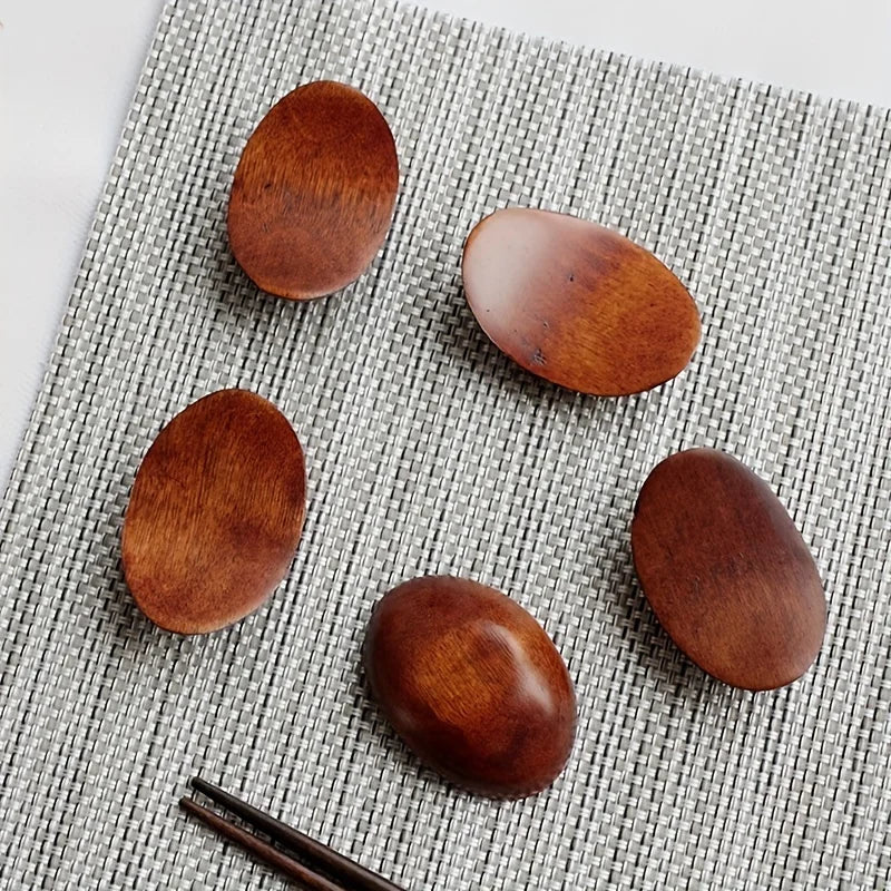 Five wooden kawaii chopstick holders on a textured gray surface