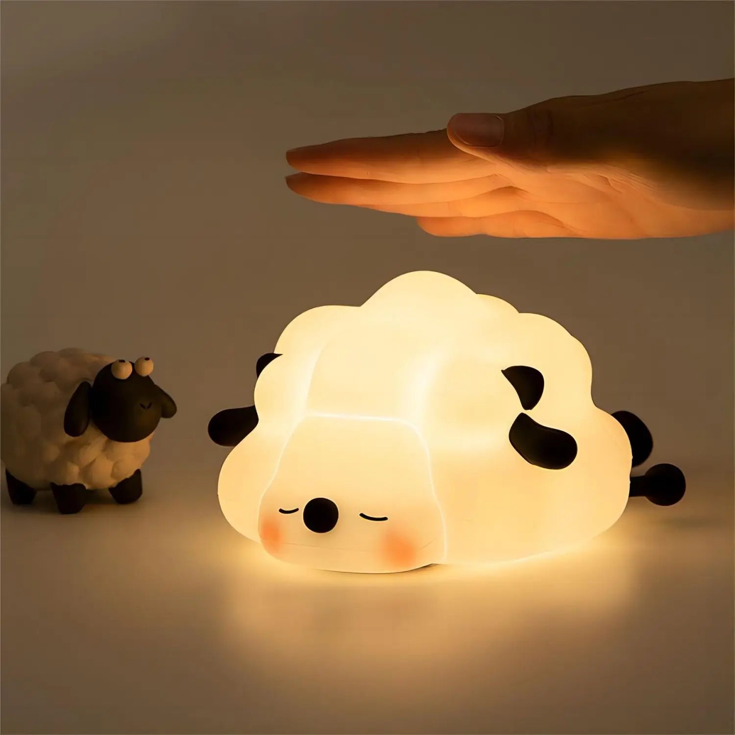 Kawaii sheep-shaped night light being touched by a hand with a dark background