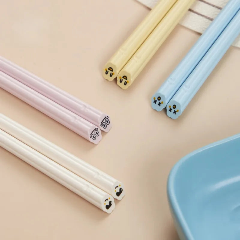 Set of colorful kawaii chopsticks with cartoon faces on a beige background