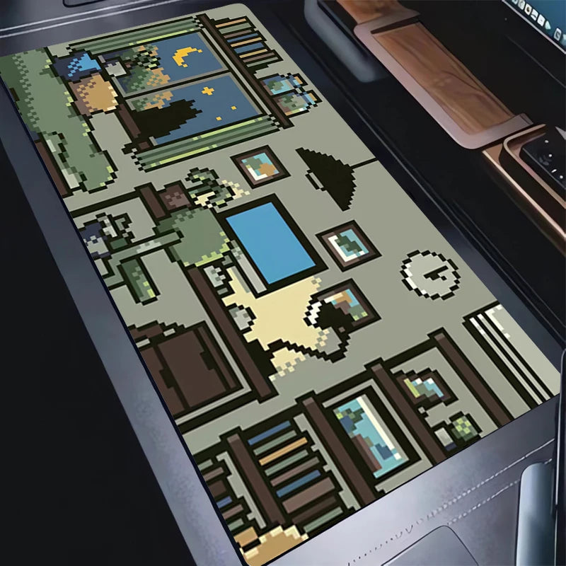 A rectangular desk mat featuring a detailed pixel-art illustration of a cozy living room and garden scene, shown placed on a dark desk next to a laptop.