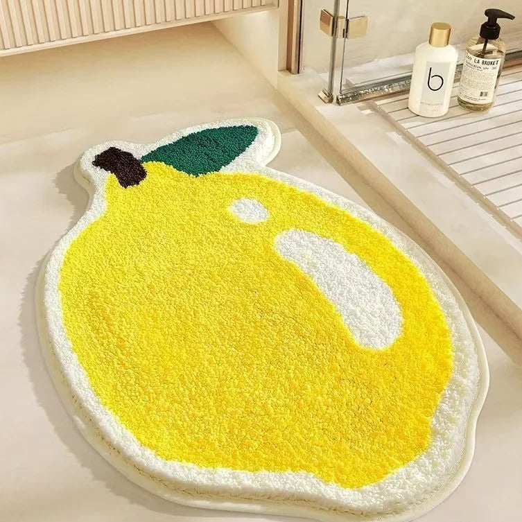 Kawaii lemon-shaped bath mat on a bathroom floor with toiletries in the background.